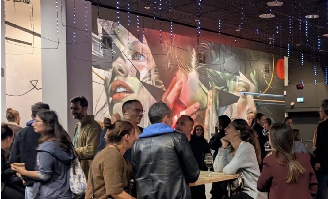 Invités au bar devant une fresque monumentale